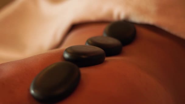 Terapia de piedra y masaje de espalda en spa de belleza. Primer plano masaje cuerpo femenino mientras que el tratamiento de spa en el hotel resort. Cuidado del cuerpo y la piel. Asistencia sanitaria y medicina alternativa . — Vídeo de stock