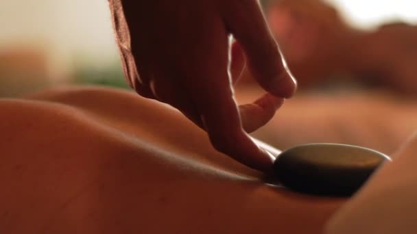 Jeune femme recevant un massage en pierre dans un spa de beauté. Soin spa et massage du corps. Concept de soins de la peau. Détente et récupération du corps. Thérapie alternative . — Video