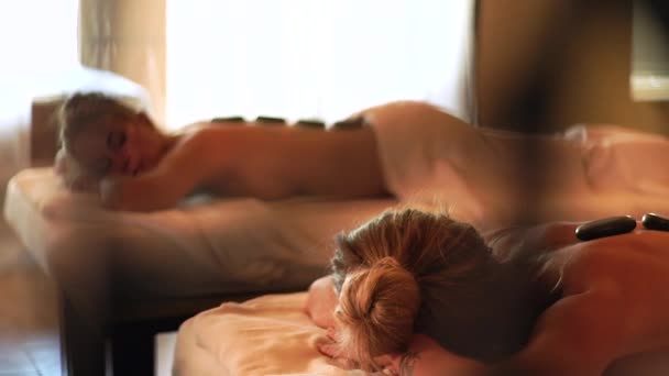 Femeia relaxantă primește masaj de piatră în salonul spa. Masaj de piatră și terapie corporală în spa. Conceptul de îngrijire a corpului și a pielii. Conceptul de relaxare zen. Sănătate și medicină . — Videoclip de stoc