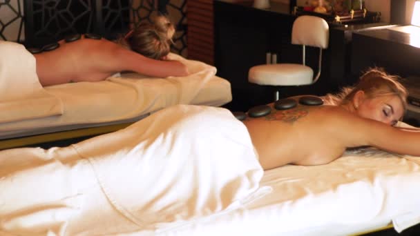 Wellness-Behandlung und Hot-Stone-Massage. schöne Frau genießt Steinmassage im Wellness-Salon. junge Frau beim Entspannen während Rückenmassage. Hautpflegekonzept. — Stockvideo