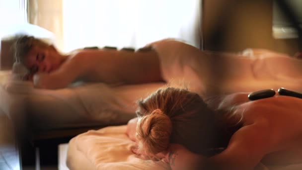 Hermosa mujer recibiendo masaje de piedra en el salón de spa. Mujer joven relajante mientras masaje de espalda con piedra caliente. Tratamiento de spa y terapia corporal. Concepto de cre piel . — Vídeos de Stock