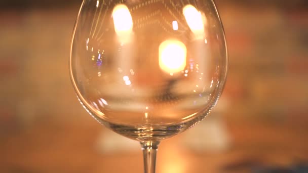 Lege wijnglas op het branden van kaarsen achtergrond. Close-up van wijnglas op avond diner tafel met kaarsen. — Stockvideo