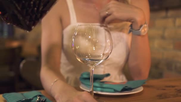 Primer plano verter vino en copa para mujer joven en la mesa de la cena en el restaurante. Mujer bebiendo vino tinto de copa en una cena romántica en un elegante restaurante . — Vídeos de Stock