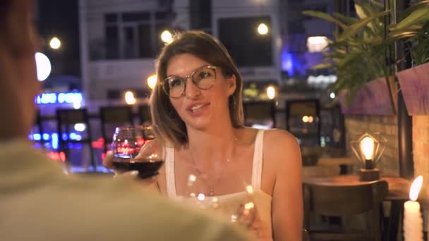 Atrakcyjna kobieta rozmawia toast podczas romantycznej kolacji i pili wino w restauracji. Młoda kobieta, picie wina z szkła razem człowiek na romantyczną randkę w kawiarni. — Wideo stockowe
