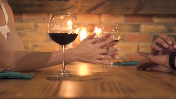 Hombre y mujer tomados de la mano mientras que la cena romántica para dos con velas en el restaurante de la noche. Las manos femeninas y masculinas en la mesa al atardecer en la cafetería elegante . — Vídeos de Stock