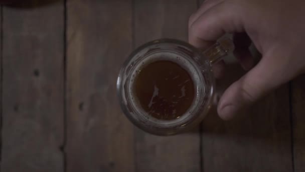 Taza de cerveza vista superior de pie en la mesa de madera en bar bar. Mano masculina tomando taza de cerveza para beber en el pub . — Vídeos de Stock