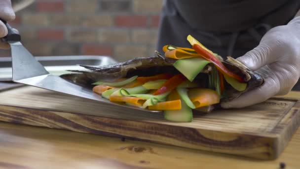 Chef cocinero poniendo en tablero de madera pescado a la parrilla con decoración vegetal. Pescado asado con verduras frescas sobre fondo de madera. Menú de mariscos en restaurante. Alimentación y dieta saludables . — Vídeos de Stock