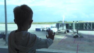 Küçük çocuk isteyen pencere süre bekleyen uçak kalkış salonda havaalanında. Genç çocuk havaalanında bekleme üzerinde terminal penceresinden uçak için arıyorum. Seyahat ve yolculuk kavramı.