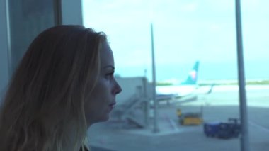 Kadın Gezgin Havaalanı terminal penceresine uçağa kalkış salonda arıyorum. Pencere bekleyen uçağın havaalanı terminal içinde süre isteyen genç kız. Seyahat ve Turizm kavramı.