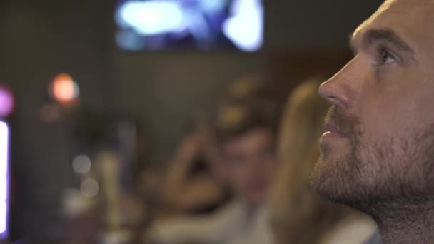 Homme barbu buvant de la bière de tasse et regardant la diffusion dans le bar de sport. Jeune homme buvant de la bière froide dans un pub sportif .