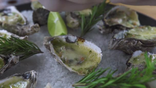 Oesters gebakken met kaas, kruiden en kalk op plaat dicht omhoog. Zeevruchten achtergrond. Mediterrane gerechten met zeevruchten. Samenstelling van de levensmiddelen en decoratie. — Stockvideo