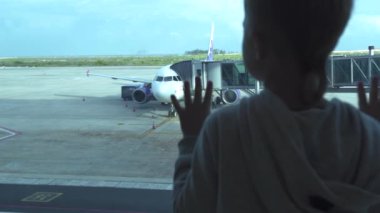 Küçük çocuk Havaalanı terminal penceresine uçağa kalkış salonda arıyorum. Çocuk seyahat sırasında bekleyen uçak Havaalanı Terminal penceresine bakarak. Seyahat ve yaz tatil kavramı.