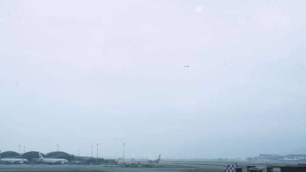 Aiplane flyger i himlen för landning i airpot terminal i Hong Kong city, Kina. Passagerarflygplan som flyger i molnig himmel över ankomstflygplats terminal. — Stockvideo