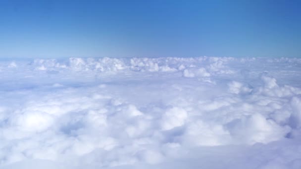 Pluizige wolken in blauwe hemel vanuit vliegtuigen venster. Uitzicht vanuit raam vliegen vliegtuig onder witte wolken in blauwe hemel. Hemel kopie ruimte achtergrond. — Stockvideo