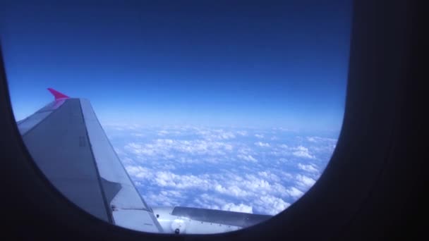 Cielo azul, nubes blancas y vista del ala desde el avión de pasajeros que vuela por la ventana. Ala de avión en nubes blancas en el cielo azul mientras vuela vista desde la ventana de la cabina . — Vídeos de Stock