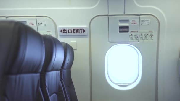 Puerta de salida de emergencia y asientos de pasajeros vacíos dentro del avión comercial. Interior moderno avión de pasajeros, sillas de pasajeros y salida de puerta de emergencia. Avión de cabina de clase económica . — Vídeo de stock