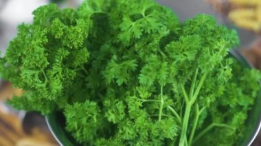 Metal kapta taze yeşil maydanoz kapatın. Maydanoz sebze salatası yemek pişirmek için. Çiğ otlar ve yeşilliklerle vejetaryen mutfağı. Sağlıklı beslenme ve diyet yiyecek. Mutfak masasında yemek arka plan.