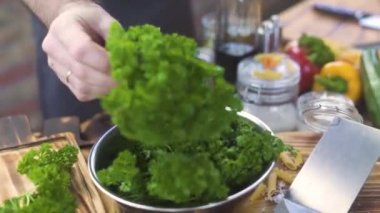 Taze maydanoz alarak ve ahşap tahta üzerinde bıçak ile kesme şef aşçı. Kesme tahtası mutfak at üzerinde yeşil maydanoz doğrama pişirin. Vejetaryen salata için madde. Sağlıklı beslenme ve diyet gıda.