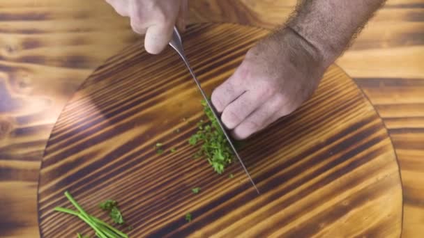 Vista superior manos cocinero corte perejil verde en tablero de madera. Chef cocinar picando perejil fresco en la tabla de cortar. Ingrediente para ensalada de verduras. Dieta vegetariana. Concepto de cocina de alimentos . — Vídeos de Stock