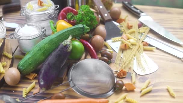 Σύνθεση των τροφίμων από φρέσκα λαχανικά, τα αυγά και μακαρόνια σε ξύλινο υπόβαθρο. Ωμά λαχανικά και συστατικό μαγειρικής πίτσα και ζυμαρικά. Ιταλική κουζίνα. Haelthy δίαιτα και διατροφή. — Αρχείο Βίντεο