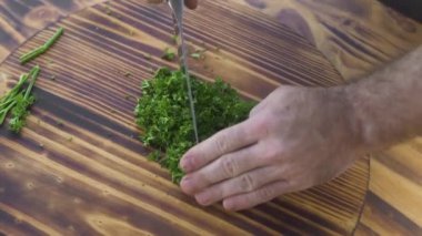 Şef yemek yeşil maydanoz ahşap tahta üstten görünüm üzerinde kesme. Taze maydanoz kesme tahtası üzerinde doğrama şef aşçı. Vejetaryen mutfağı için taze madde. Vejetaryen diyet. Pişirme gıda kavramı.