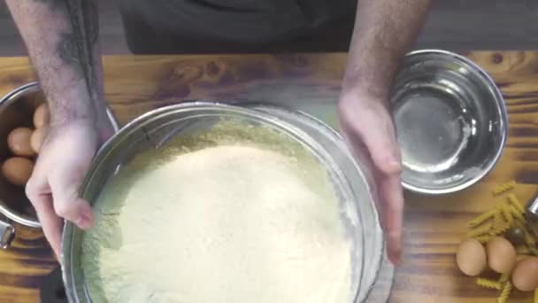 Top vista chef cozinheiro peneirando farinha em pó através da peneira para cozinhar massa de farinha. Baker derramando farinha através da peneira na cozinha da padaria. Ingredientes de preparação para pizza e massa. Conceito de massa de cozinhar . — Vídeo de Stock