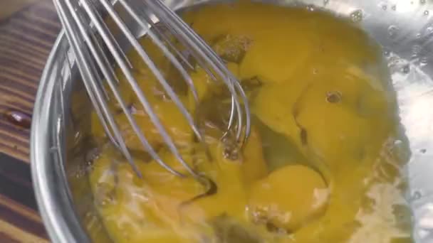 Sluiten kloppen eieren met de keuken garde in metalen kom voor 's morgens omelet of roerei. Kook eieren voor het maken van deeg in de bakkerij. Ontbijtconcept koken. — Stockvideo