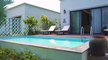 Bahçeden lüks villa görünümünde yüzme havuzu ile modern bir ev. Bahçede tropikal palmiye yakınında dinlenmek için yüzme havuzu ve veranda ile Mimari lüks villa.