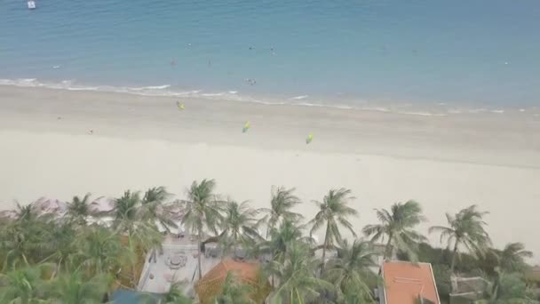 Люди плавають у блакитному морі на пляжі. Кольорові каяки лежать на піщаному пляжі і туристи, які плавають в океані. Вид з повітря літній курорт на морському узбережжі . — стокове відео
