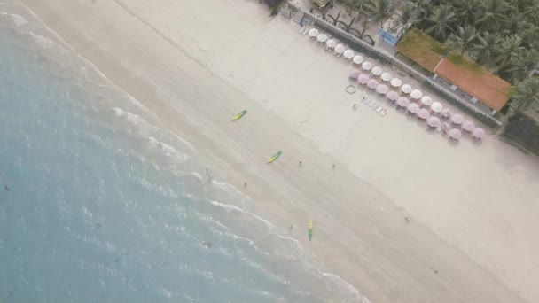 Sombrillas de vista aérea en la playa del hotel resort y gente nadando en el mar azul. Turistas descansando en la playa del resort y nadando en el mar en vacaciones de verano . — Vídeo de stock