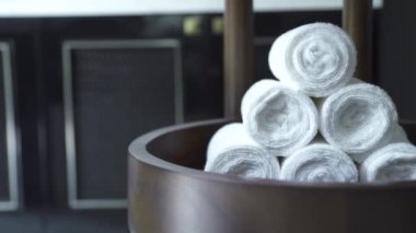 Beyaz rulo havlu, koyu arka planda modern kaplıca salonunda yığılmış. Siyah banyoda beyaz banyo havlusu. Duş, sauna ve banyo için aksesuarlar..