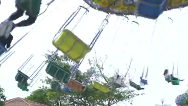 People riding on chain carousel attraction in amusement park. Happy friends having fun on colorful carousel in amusement park at summer weekend. — Stock Video