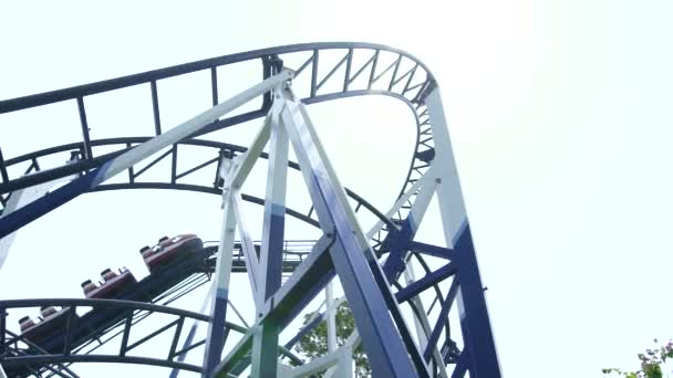 Roller coaster ride working in amusement park. Moving extreme attraction switchback at amusement park. Low angle view. — Stock Video