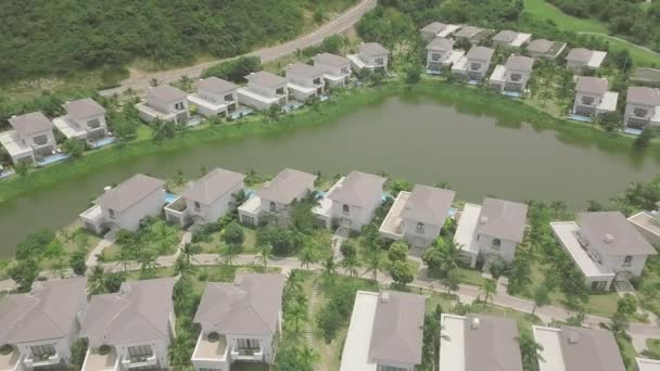 海岸に家、スイミングプール、湖を備えた空中風景豪華なコテージ村。緑の芝生と湖の背景にドローンビューリゾートヴィラ. — ストック動画