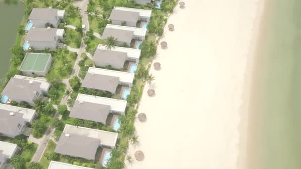 Drone vista villaggio turistico villa e villa con piscina sulla spiaggia sul mare. Villaggio cottage di lusso con piscina sulla riva blu del mare. Architettura del paesaggio aereo hotel turistico sulla costa dell'oceano . — Video Stock
