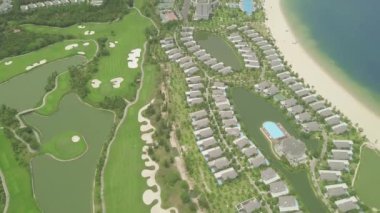Tropikal ada ve uçan drone mavi deniz manzara üzerinde lüks villa ve tatil otelleri. Mavi deniz kıyısında evler, yüzme havuzu ve golf sahası ile Hava manzara lüks yazlık köy.