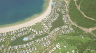 Mavi denizde tropikal adada lüks konak ile modern yazlık köy. Deniz kıyısında evler, yüzme havuzu ve golf sahası ile havadan görünüm mimarisi lüks köy.