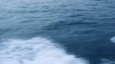 Yüzen gemiden mavi deniz yüzeyinde su izi yakın. Köpük ve dalgalar, dökülmeler, kabarcıklar, yelkenli tekne izleri ile Trail turkuaz deniz suyu.