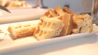 Otel restoranında açık büfe de beyaz tabakta yatan geleneksel Belçika waffle'ları. Sabah kahvaltısı için tatlı pişmiş waffle. Tatlı gıda kavramı. Diyet ve beslenme.