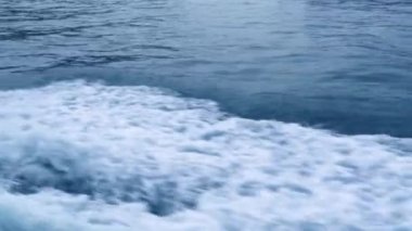 Yüzen gemiden mavi deniz yüzeyinde su izi yakın. Köpük ve dalgalar, dökülmeler, kabarcıklar, yelkenli tekne izleri ile Trail turkuaz deniz suyu.