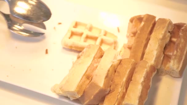 Hand taking belgian waffles lying on white plate on buffet in hotel restaurant. Sweet baked waffles for morning breakfast. Dessert food concept. Dieting and nutrition. — Stock Video