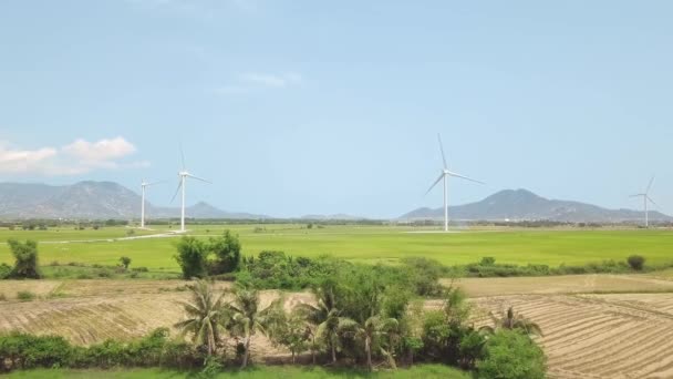 Mavi gökyüzü ve dağ manzarasında yeşil tarımsal alanda rüzgar türbini yenilenebilir enerji. İHA 'dan yel değirmeni türbini hava görüntüsü. Temiz yenilenebilir alternatif enerji üretiliyor. — Stok video