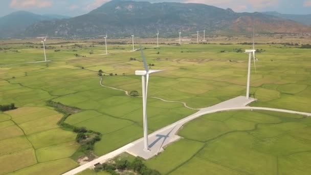 Windmill energy plant power turbine in agricultural field. Aerial view wind power generating farm on green field, mountain landscape. Generation clean renewable alternative energy. Ecology friendly — 비디오