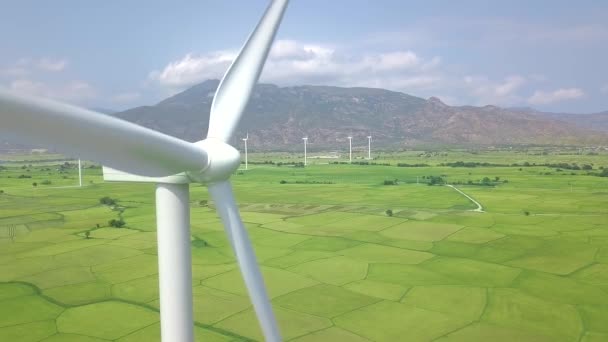 青い空と山の風景の風車。クリーン再生可能エネルギーの空中ビューのための風力発電機。緑のフィールドにドローンビュー風力発電所。代替エネルギー源生態系の保全. — ストック動画