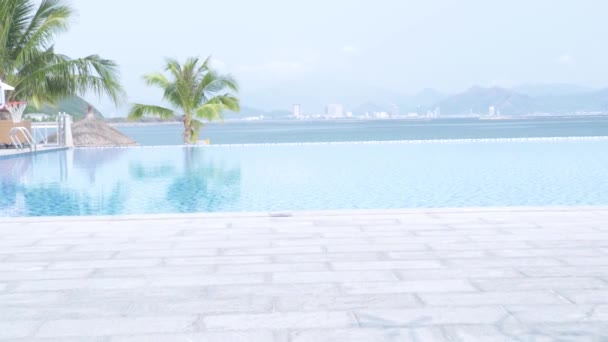 Blue infinity pool on palm trees and sea landscape. Luxury swimming pool on resort hotel on big city and blue sea landscape. — Stock Video