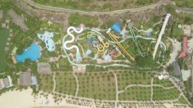 Drone mavi deniz plajında eğlence aquapark renkli su slayt görünümü. İnsanlar yeşil palmiye ağacı manzara açık su parkı slaytlar üzerinde sürme eğlenin. Yaz etkinliği.
