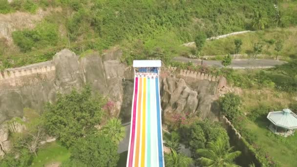 暑假时，人们在游乐园里滑上五颜六色的水滑梯。空中景观。在户外水上乐园无人机视图中，人们在滑梯上玩得开心. — 图库视频影像