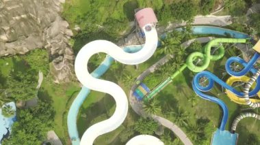 Drone eğlence aquapark renkli su kaydırağı görünümü. Açık su parkında kaydıraklara binerken eğlenen insanlar. Yaz etkinliği.