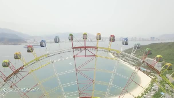 Vista aérea roda gigante no parque de diversões no mar, montanha e paisagem moderna da cidade. Parque de diversões com grande roda gigante do drone acima . — Vídeo de Stock