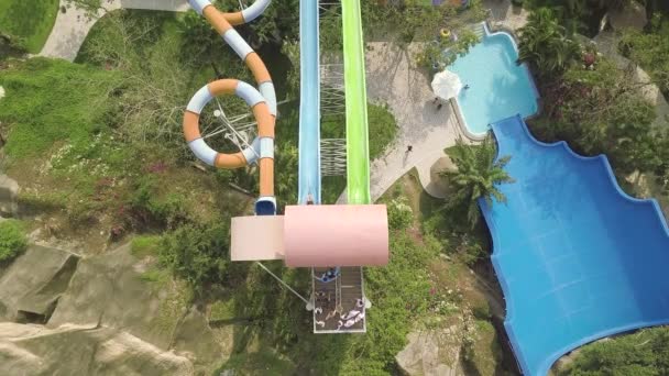 Toboganes de agua de colores en el parque acuático de atracciones en las vacaciones de verano. Vista aérea. Personas que se divierten montando en toboganes en el parque acuático al aire libre en vacaciones de verano . — Vídeo de stock